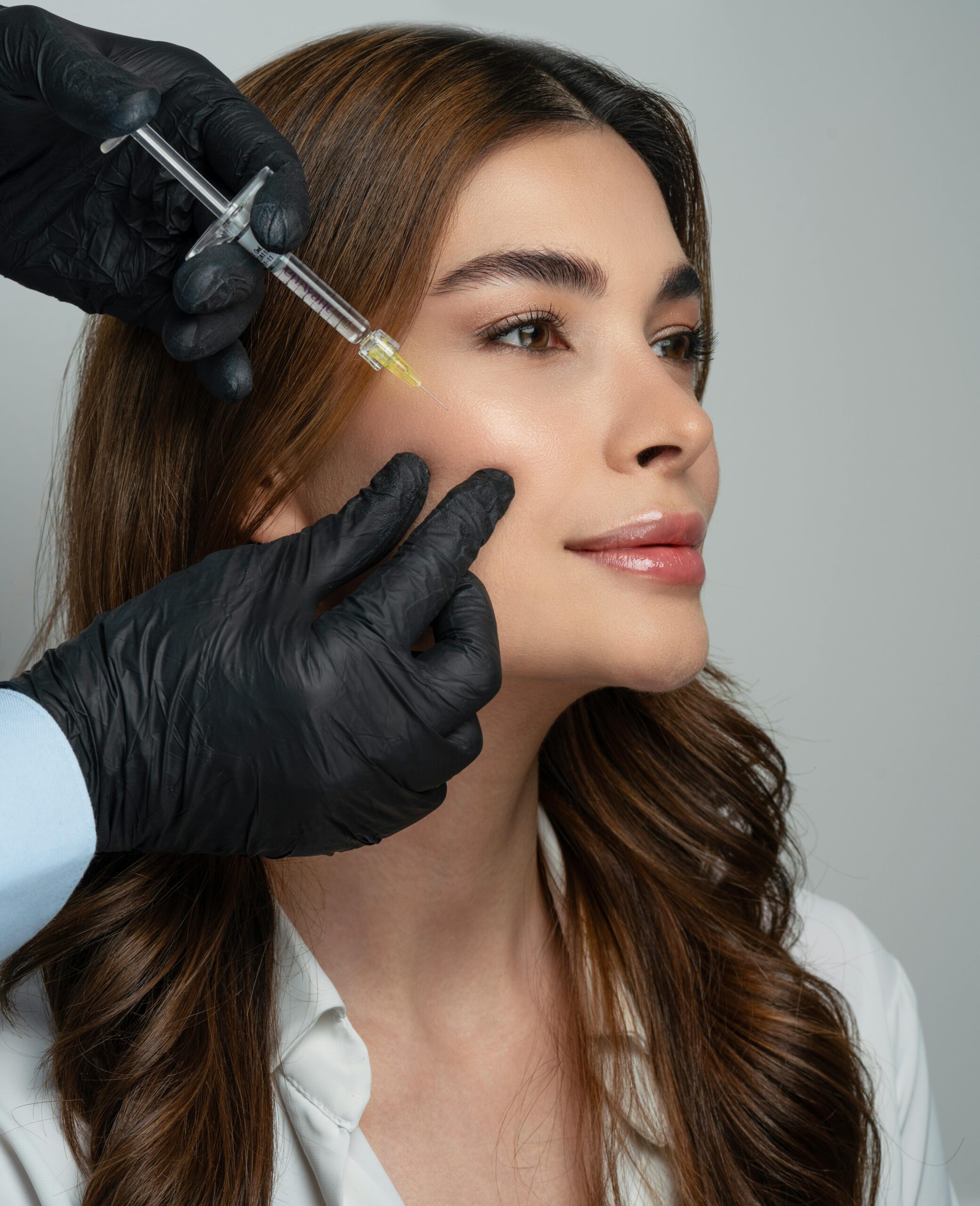 Home A dermatologist administers a dermal filler injection to a woman's face, enhancing facial aesthetics.